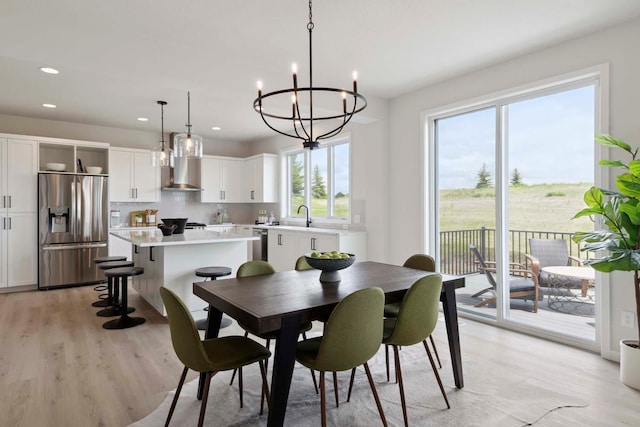 dining room with recessed lighting, light wood-style flooring, and a notable chandelier