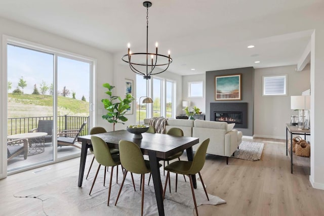 dining room featuring a notable chandelier, light wood-style flooring, a healthy amount of sunlight, and baseboards