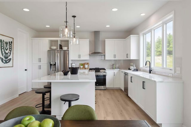 kitchen featuring stainless steel appliances, plenty of natural light, wall chimney range hood, and a sink