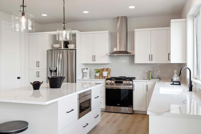 kitchen featuring appliances with stainless steel finishes, a sink, backsplash, and wall chimney exhaust hood