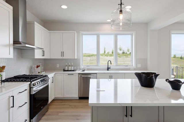 kitchen featuring tasteful backsplash, stainless steel appliances, wall chimney exhaust hood, and a sink
