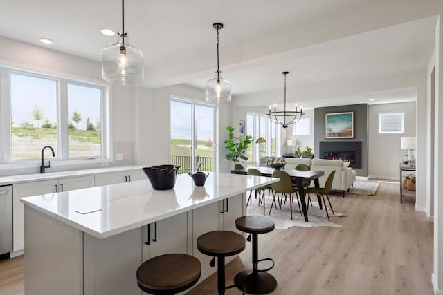 kitchen featuring a sink, a kitchen island, light wood-style flooring, and a glass covered fireplace