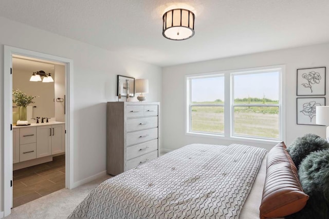 bedroom featuring light tile patterned floors, connected bathroom, a sink, light colored carpet, and baseboards