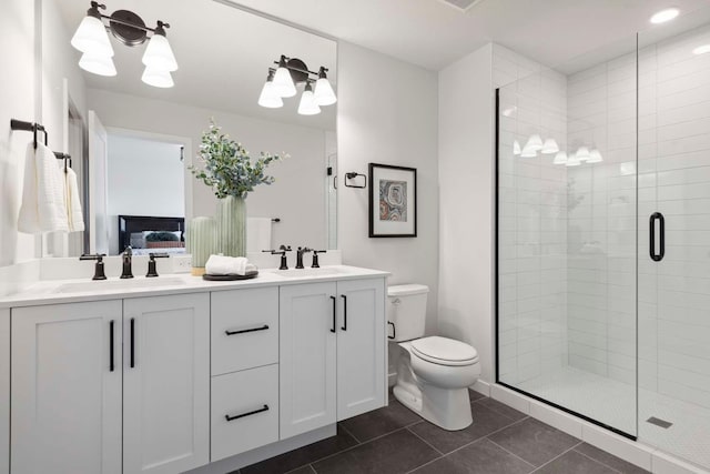bathroom featuring double vanity, toilet, a shower stall, and a sink