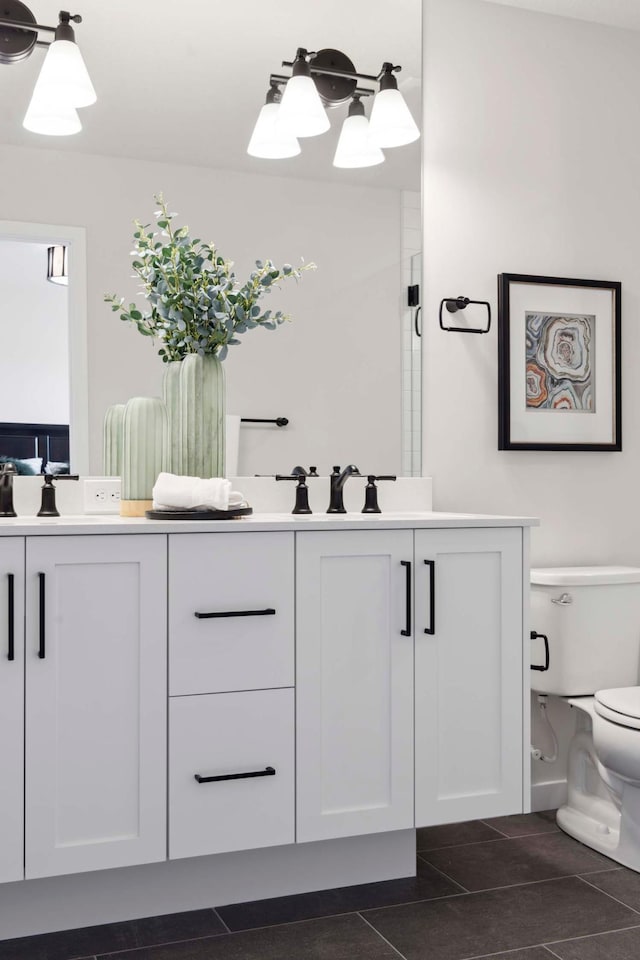 full bathroom featuring toilet, a sink, double vanity, and tile patterned floors