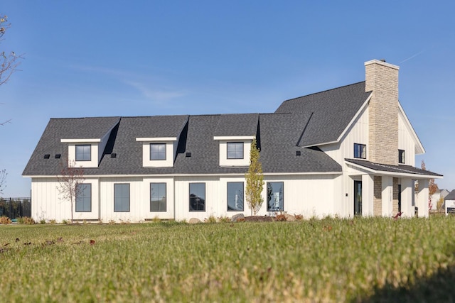 modern farmhouse with a chimney, board and batten siding, a shingled roof, and a front yard