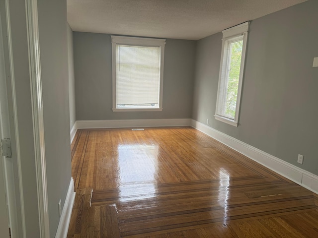 unfurnished room with baseboards, a textured ceiling, and wood finished floors
