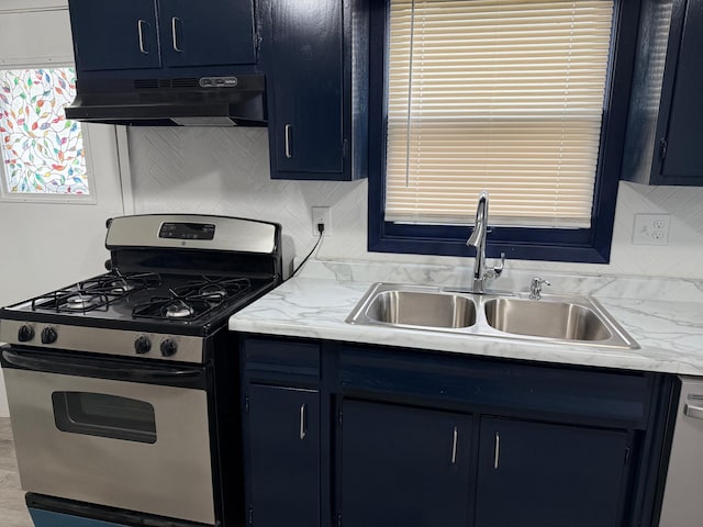 kitchen with stainless steel range with gas stovetop, under cabinet range hood, a sink, blue cabinets, and light countertops
