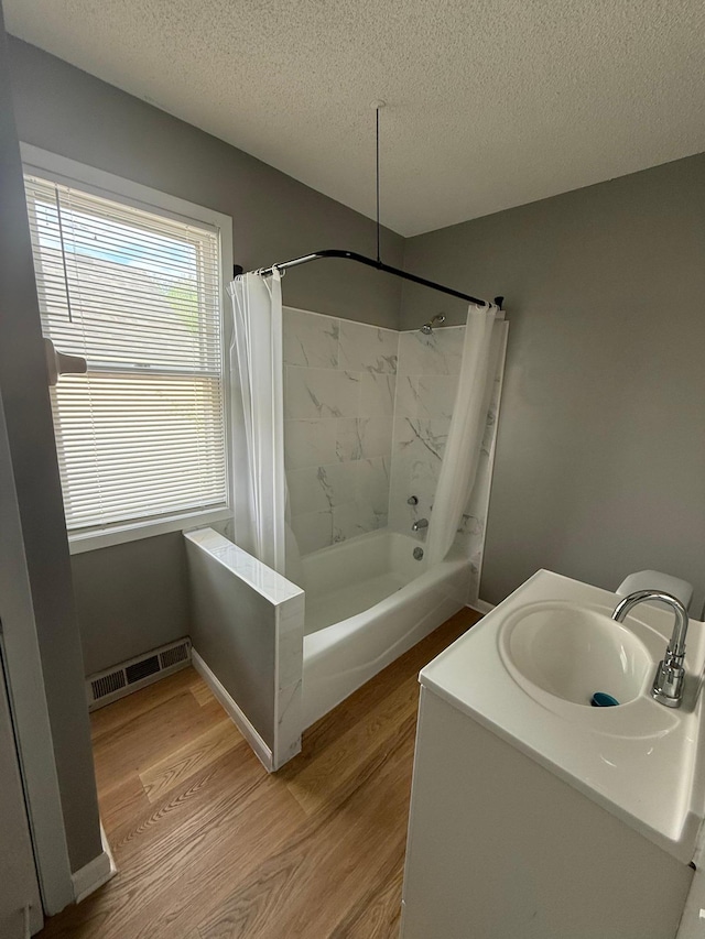 bathroom with a sink, wood finished floors, a textured ceiling, and shower / bathtub combination with curtain