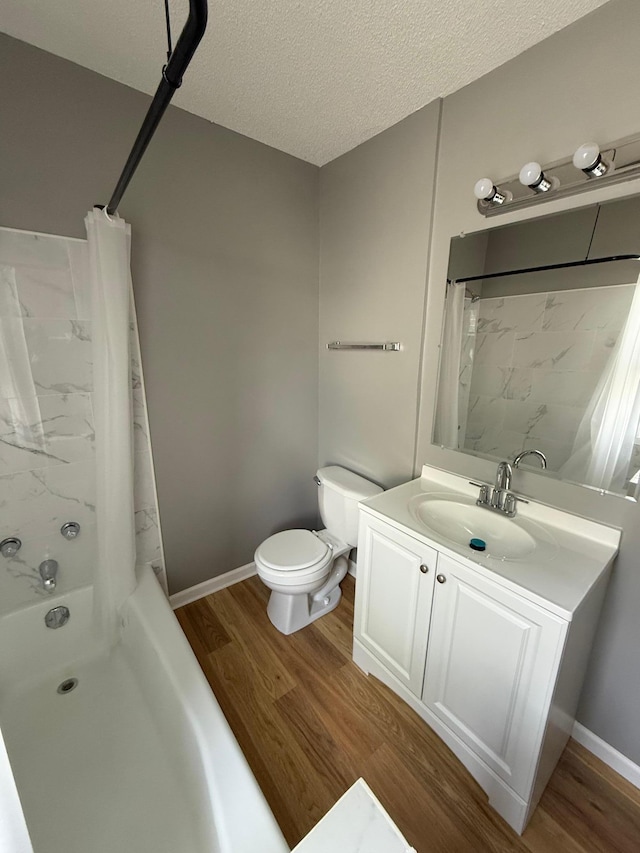 bathroom featuring wood finished floors, toilet, vanity, a textured ceiling, and shower / bath combo