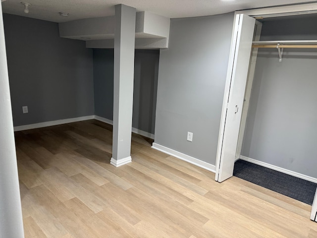 unfurnished bedroom featuring light wood-style flooring, a closet, and baseboards
