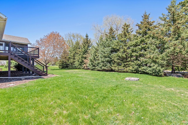 view of grassy yard featuring stairway and a deck