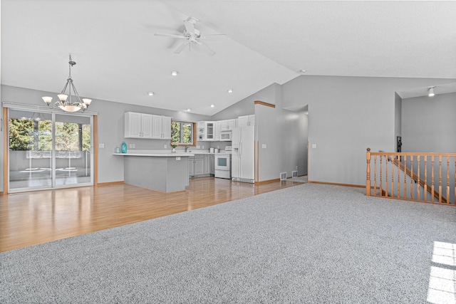 unfurnished living room with light colored carpet, a ceiling fan, a chandelier, baseboards, and recessed lighting