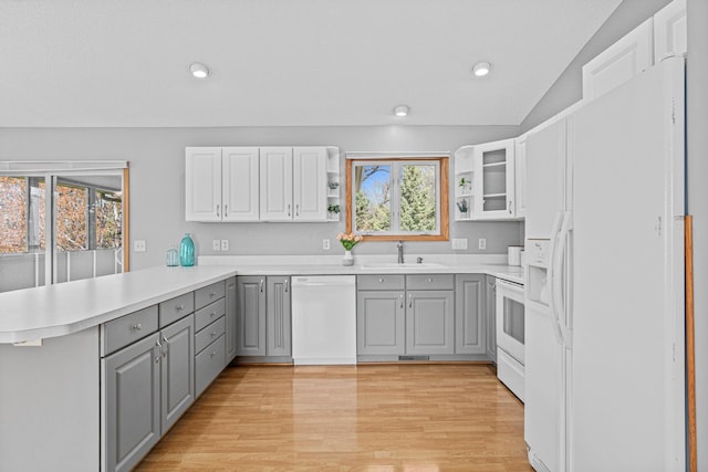 kitchen featuring white appliances, gray cabinets, a sink, a peninsula, and light countertops