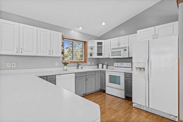 kitchen with white appliances, gray cabinets, a sink, lofted ceiling, and white cabinets