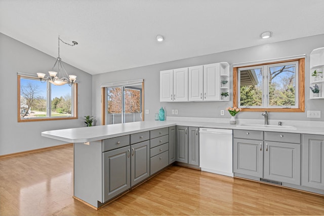 kitchen featuring white dishwasher, gray cabinetry, a sink, open shelves, and a peninsula