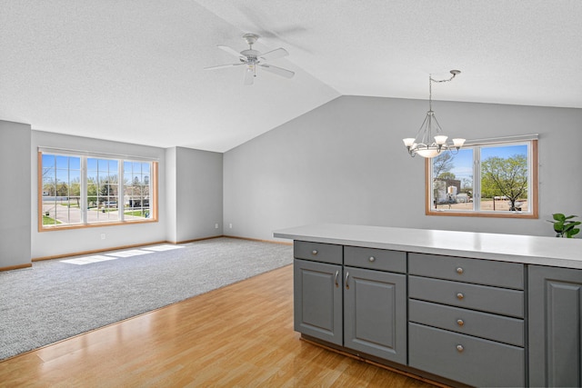 kitchen featuring gray cabinetry, vaulted ceiling, open floor plan, a chandelier, and light countertops