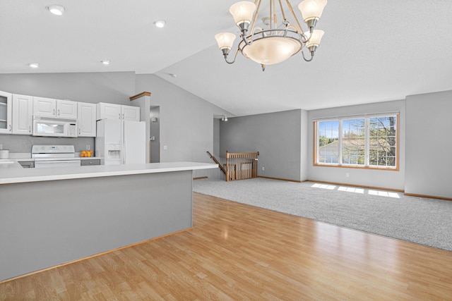 kitchen featuring white appliances, a chandelier, lofted ceiling, light countertops, and white cabinets