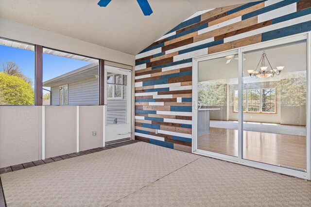 unfurnished sunroom featuring ceiling fan, vaulted ceiling, a chandelier, and plenty of natural light