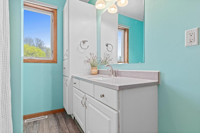 bathroom with wood finished floors, vanity, and baseboards