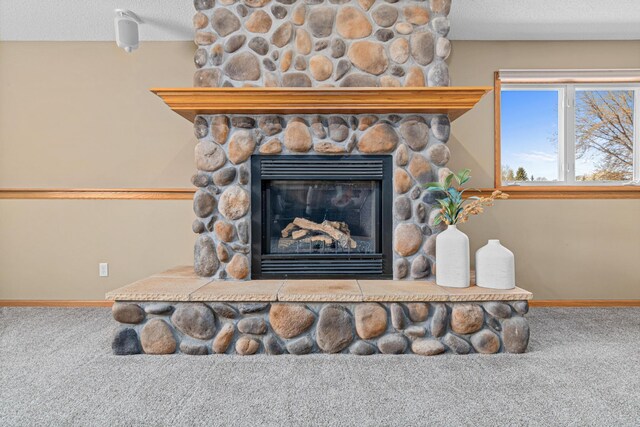 detailed view of carpet flooring, baseboards, a stone fireplace, and a textured ceiling