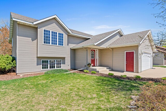 tri-level home featuring an attached garage, concrete driveway, a front lawn, and a shingled roof