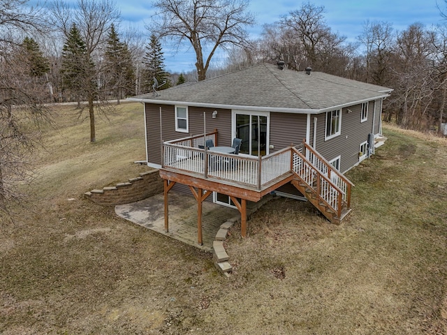 rear view of house with a wooden deck, a shingled roof, and a yard