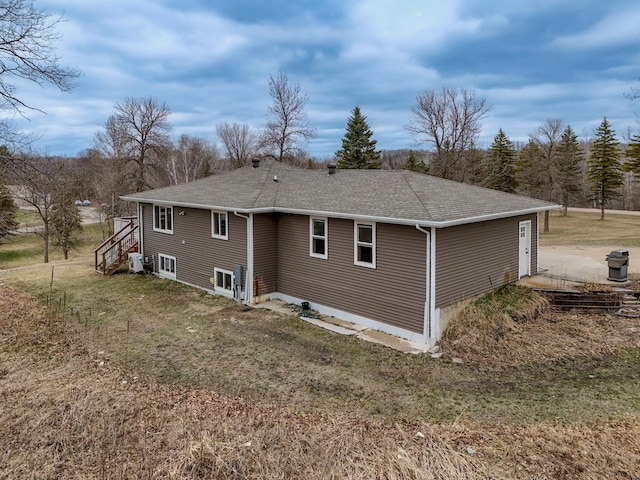 rear view of house featuring roof with shingles and a yard