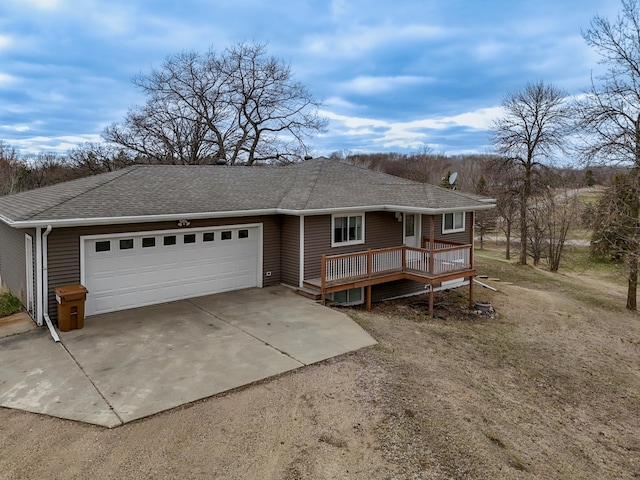 ranch-style home featuring roof with shingles, a wooden deck, concrete driveway, and a garage