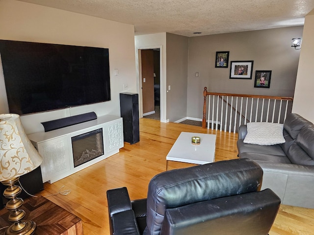living room featuring baseboards, a textured ceiling, and wood finished floors