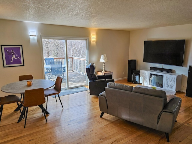 living area featuring baseboards, a textured ceiling, and light wood-style flooring