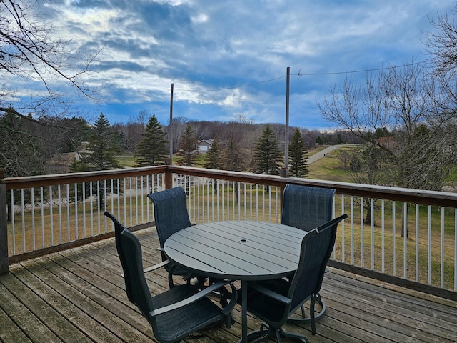 wooden terrace with outdoor dining area and a lawn