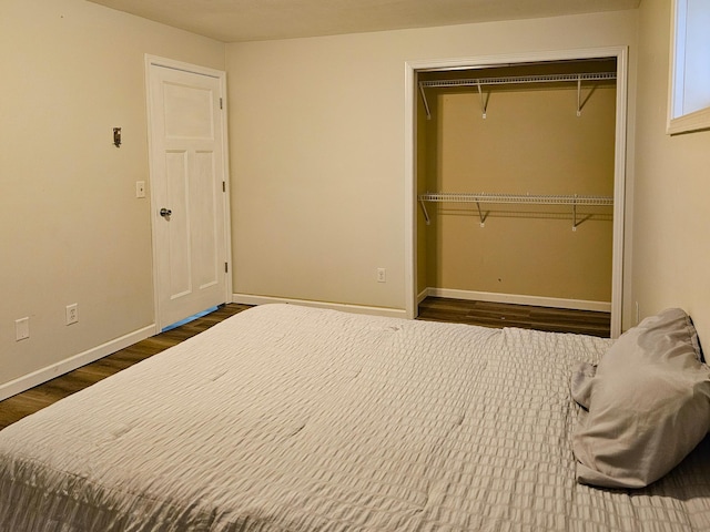 bedroom with baseboards, dark wood finished floors, and a closet