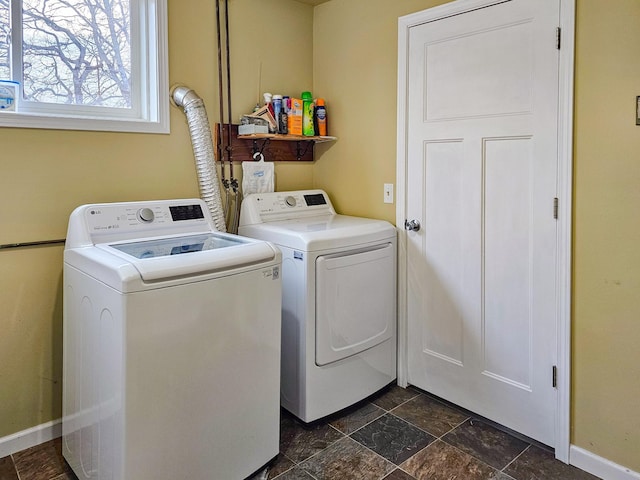 laundry room featuring laundry area, stone finish flooring, baseboards, and washing machine and clothes dryer