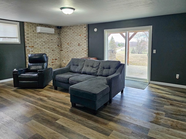 living area with an AC wall unit, baseboards, wood finished floors, and brick wall