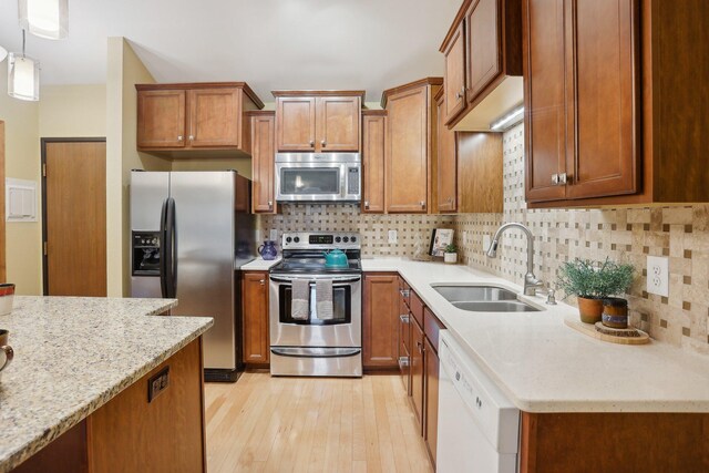 3850 Plymouth Blvd Unit 318, Plymouth, MN 55446 - kitchen with appliances with stainless steel finishes, a sink, light wood-style floors, brown cabinetry, and decorative backsplash
