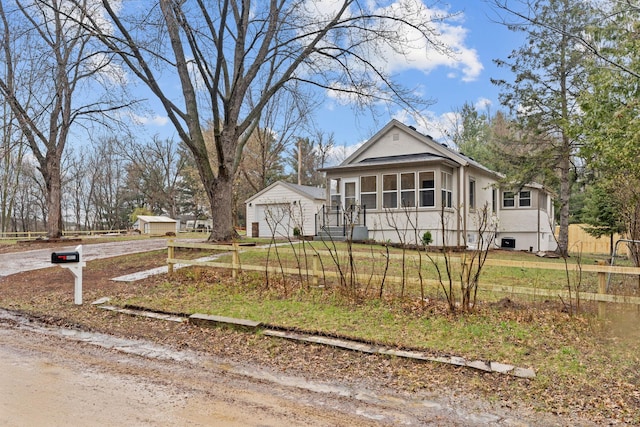 view of front of house with a garage, an outbuilding, fence, dirt driveway, and stucco siding
