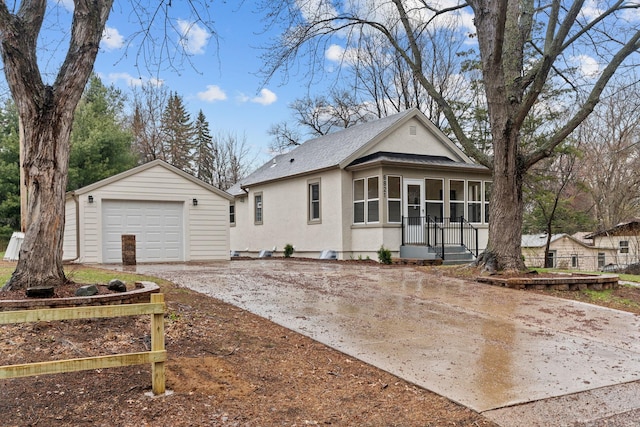 view of front of property with concrete driveway, an outbuilding, a shingled roof, stucco siding, and a detached garage