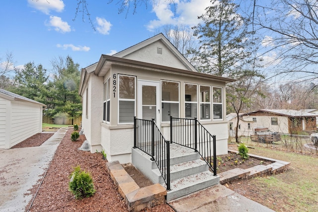 shotgun-style home featuring stucco siding, fence, and a sunroom
