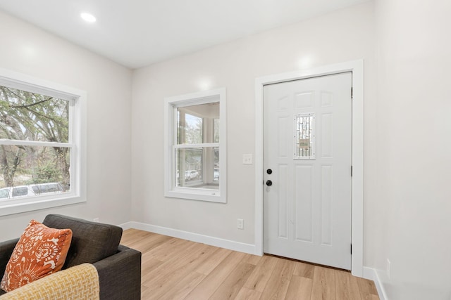 foyer with healthy amount of natural light, light wood-style floors, and baseboards