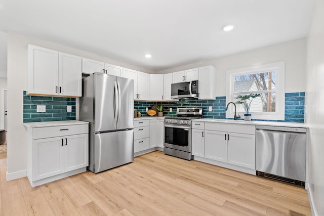 kitchen featuring stainless steel appliances, a sink, light countertops, and recessed lighting
