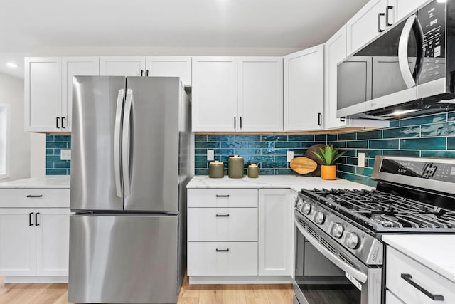 kitchen with appliances with stainless steel finishes, white cabinets, light wood-style floors, backsplash, and light stone countertops