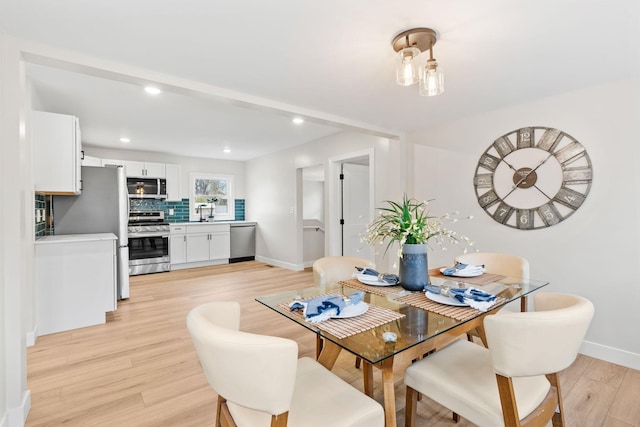 dining room featuring light wood finished floors, baseboards, and recessed lighting