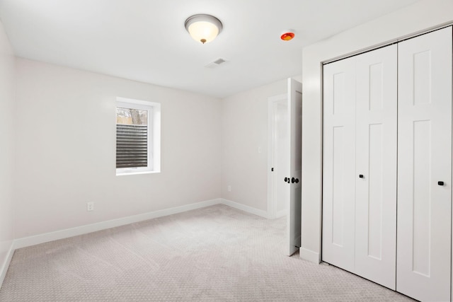 unfurnished bedroom with light carpet, baseboards, and a closet