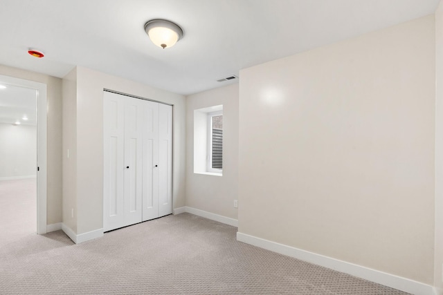 unfurnished bedroom with light colored carpet, baseboards, and a closet