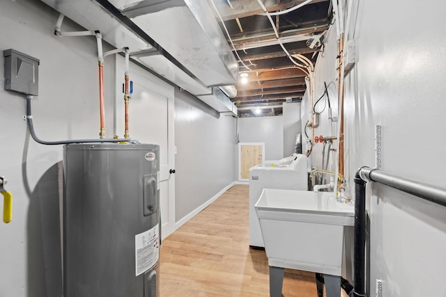 finished basement with electric water heater, washer / dryer, light wood finished floors, and a sink