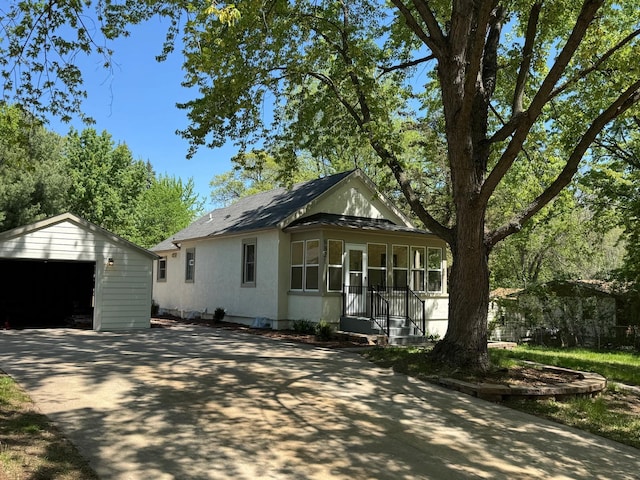 view of front of home with a garage, an outdoor structure, concrete driveway, and a shingled roof
