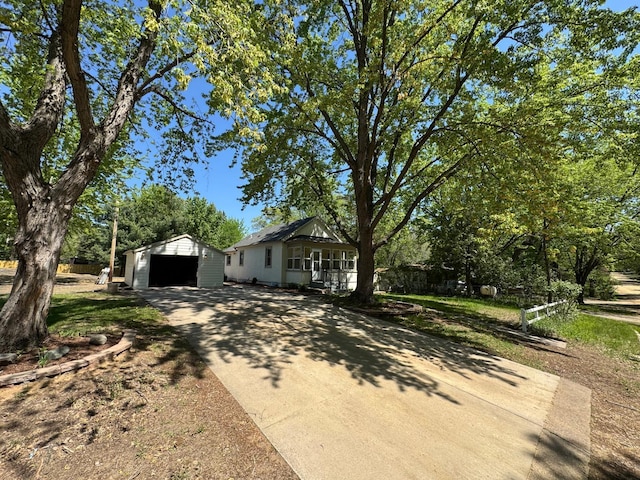 view of front facade featuring a detached garage, concrete driveway, and an outdoor structure