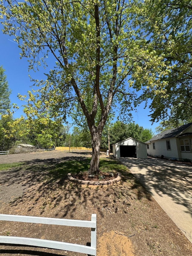 view of yard with an outdoor structure, fence, driveway, and a detached garage