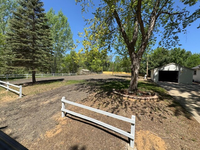 view of yard with a garage, fence, and an outdoor structure